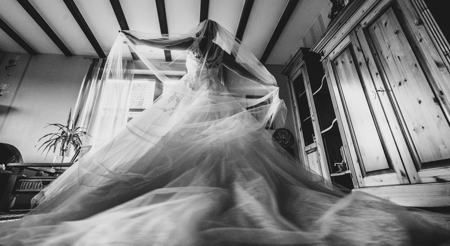 Getting ready Getting ready: Eine Braut zieht ihr Hochzeitskleid an und dreht sich vor dem Fenster.